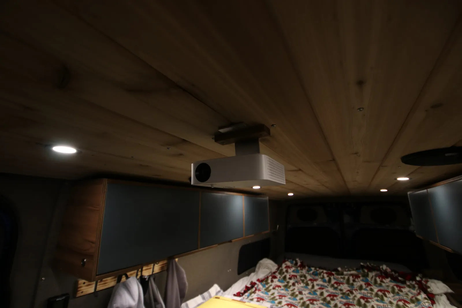 Ceiling-mounted projector on cedar plank ceiling in Rapp Sprinter van