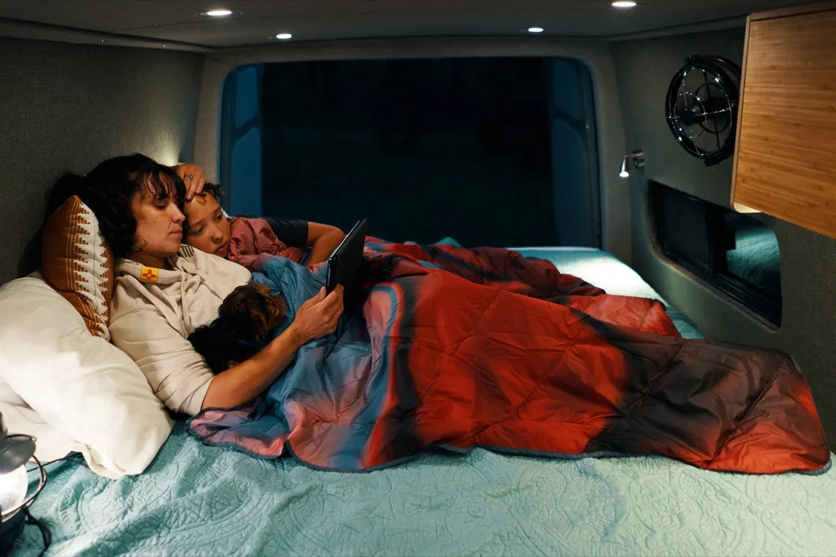 Scout van conversion cozy floating bed with family reading together at night by The Vansmith